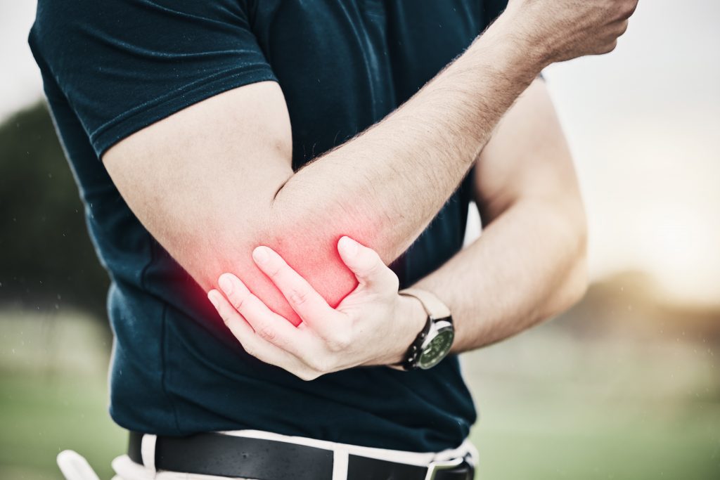 Man holding his arm at the elbow with redness around the elbow.