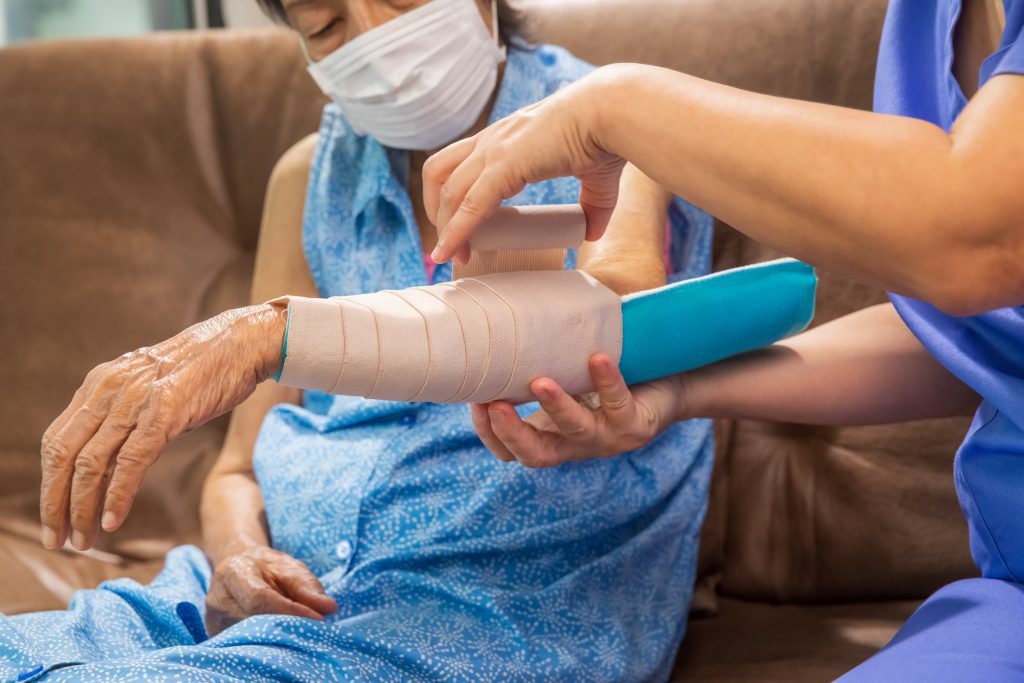 Elderly patient having an elbow splint affixed to their left arm.